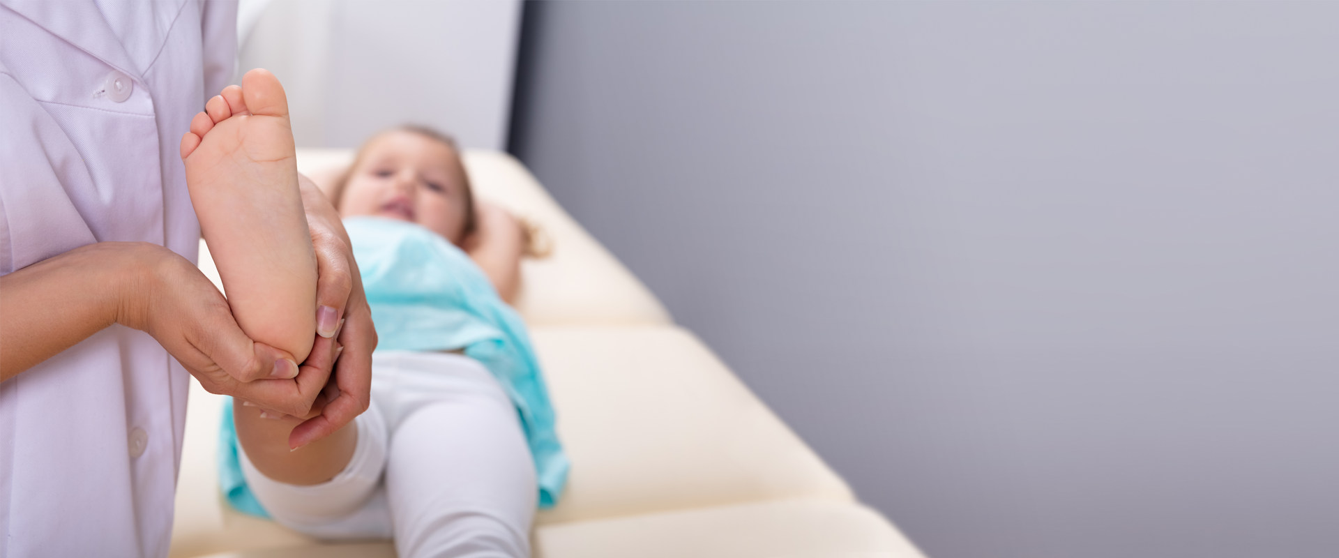 Mädchen liegt auf einem Behandlungstisch und wird auf Zehenspitzengang untersucht